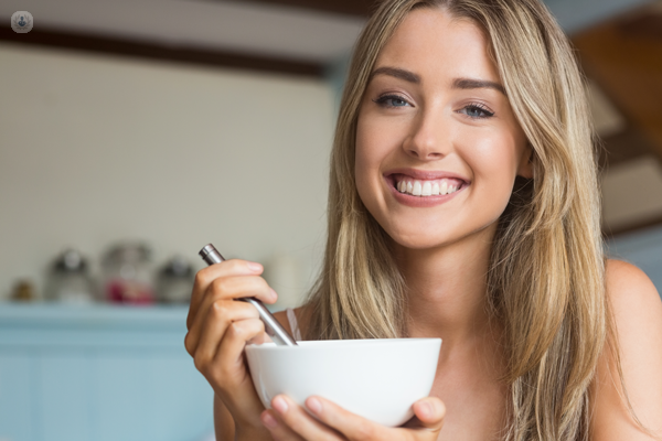 Donna che sorride mangiando una ciotola di latte e cereali