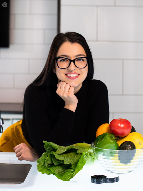 ragazza sorridente che mangia tanta frutta e verdura