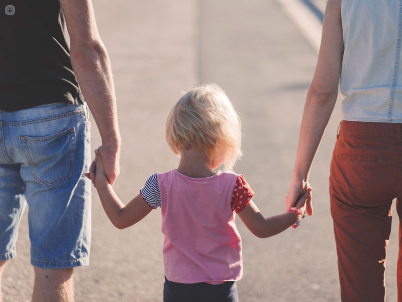 bambina che cammina mano nella mano con i genitori