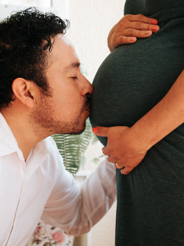 futuro papà che bacia il pancione della futura mamma