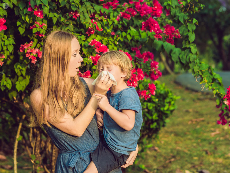 bimbo in braccio alla mamma che starnutisce