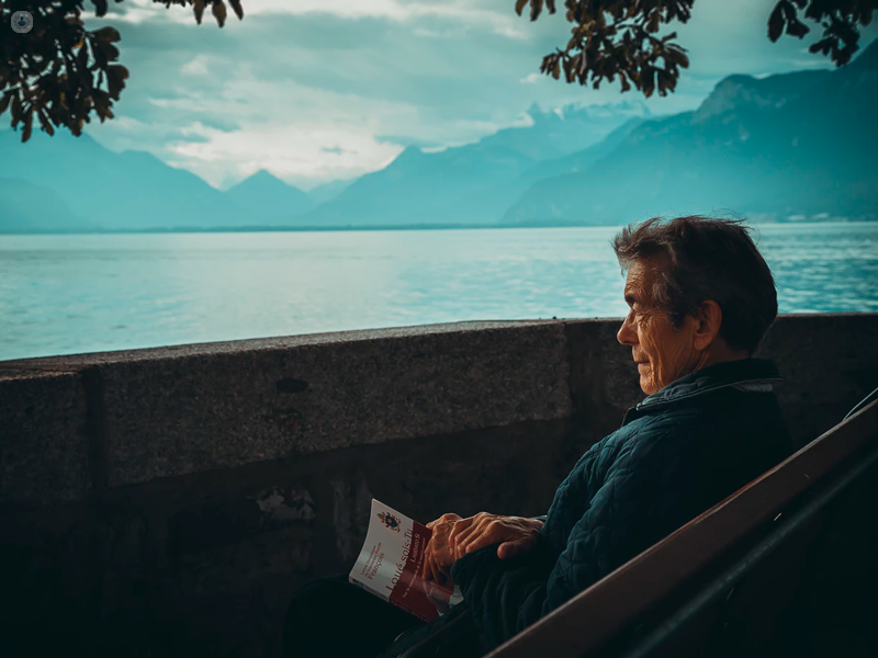 Anziano seduto che guarda il lago