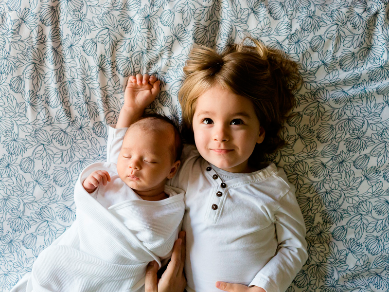 bambina e neonato sul letto
