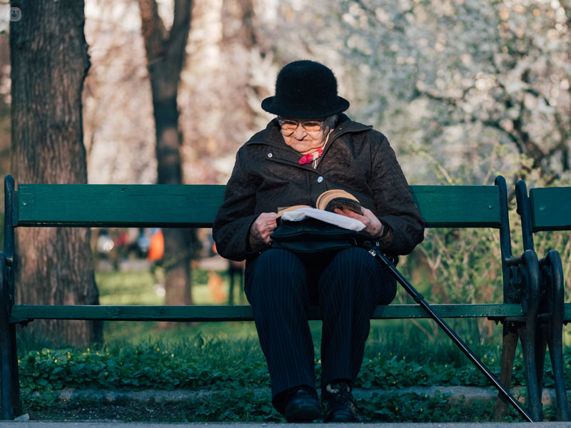anziana che legge un libro seduta su una panchina