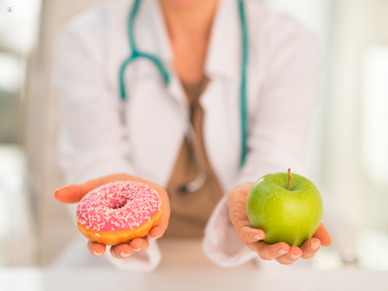 dottoressa con in mano un donut e una mela