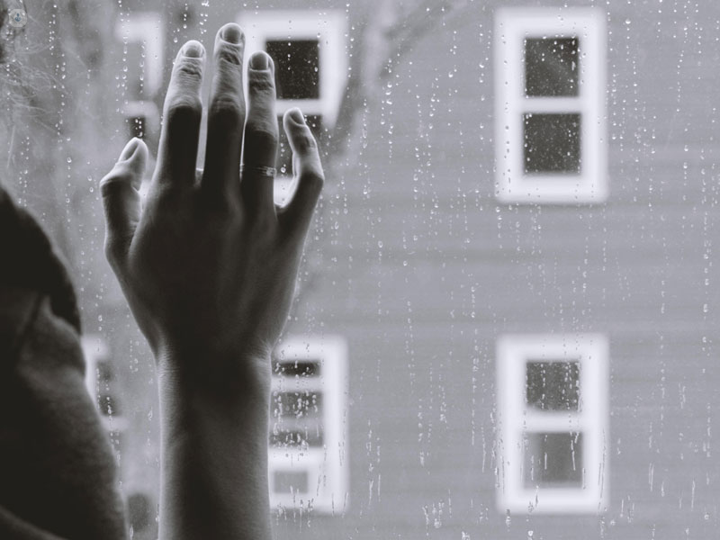 mano di una persona alla finestra mentre piove
