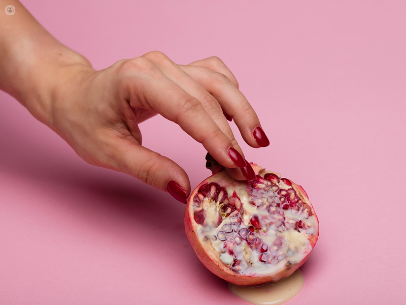 mano di una donna su una melograna
