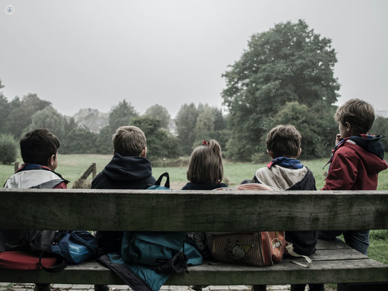 bambini girati di spalle seduti su una panchina in un parco