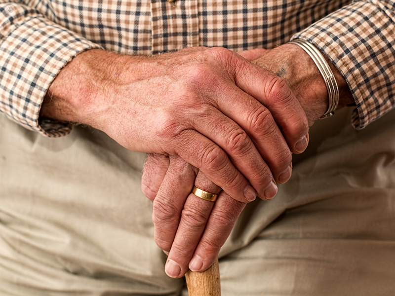 mani di un uomo anziano che si appoggiano a un bastone