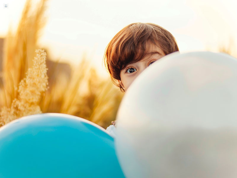 bimbo che si nasconde dietro a due palloncini