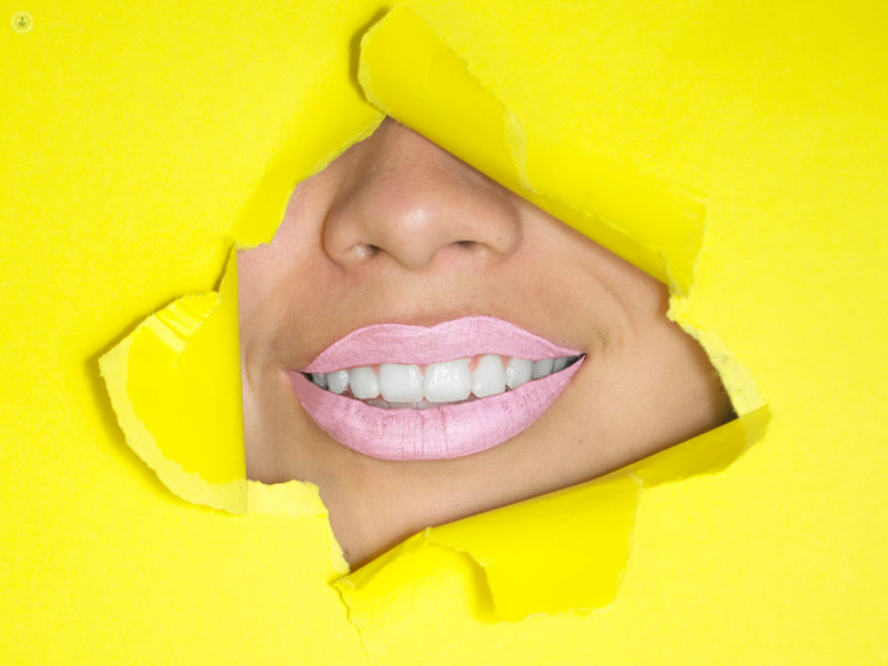 bocca di una ragazza che sorride dietro a un cartello giallo