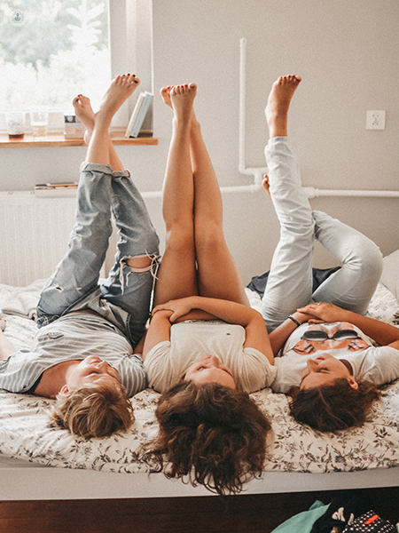 tre ragazze su un letto con le gambe in alto