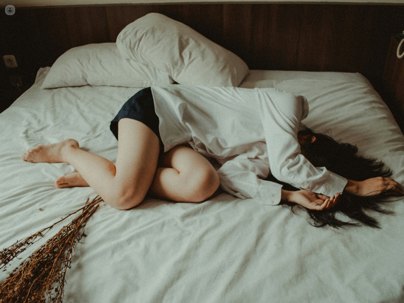 ragazza stesa sul letto con dolore a causa della vulvodinia 