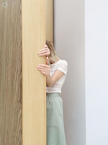 ragazza che si nasconde dietro una porta